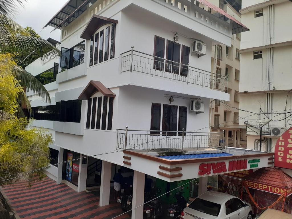 a white building with a balcony on a street at Shiva Inn in Guruvāyūr