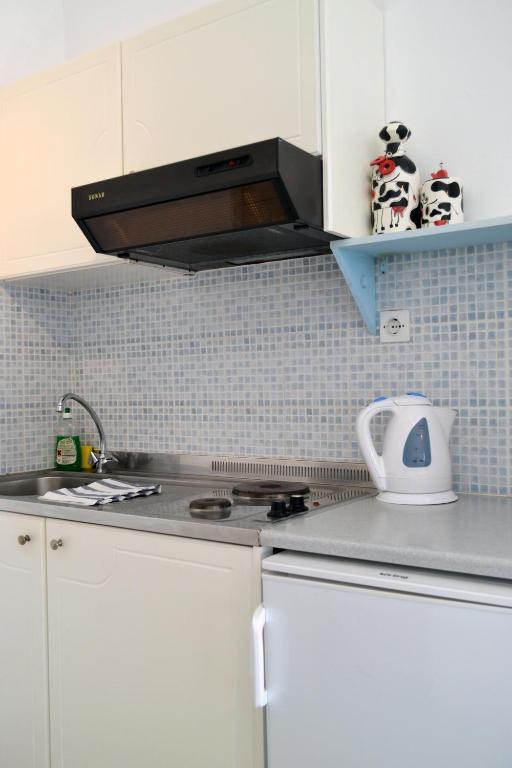 a kitchen with white cabinets and a stove top oven at Paleochori Studios in Paliochori