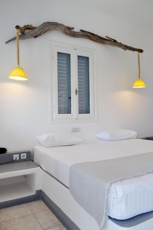 a white bedroom with two beds and two lights at Paleochori Studios in Paliochori