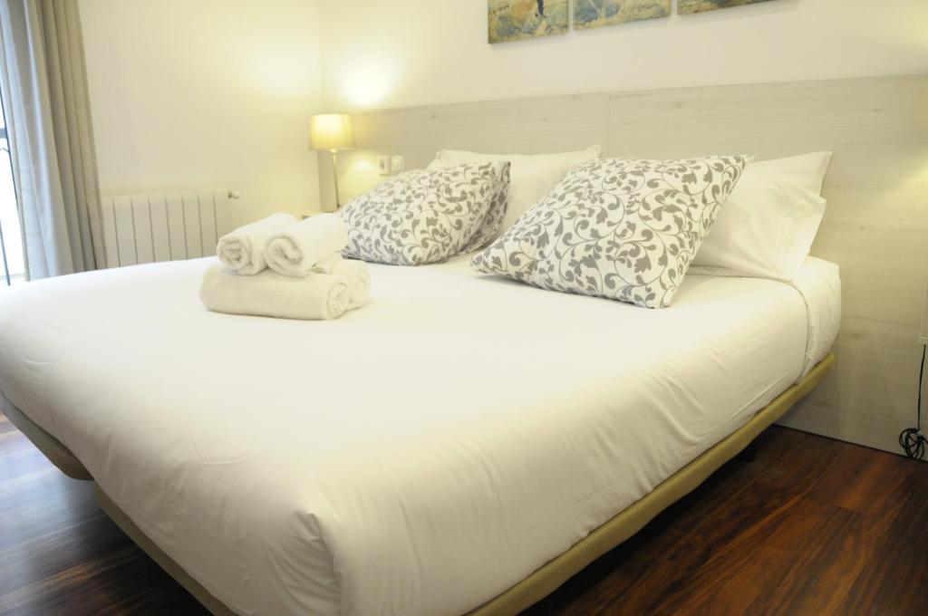 Una cama blanca con almohadas y toallas. en Pensión Old City House, en San Sebastián
