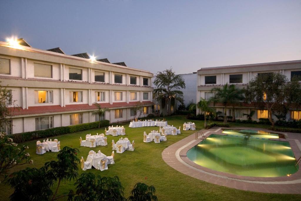 un patio con mesas y sillas blancas frente a un edificio en Hotel Express Residency-Jamnagar en Sika
