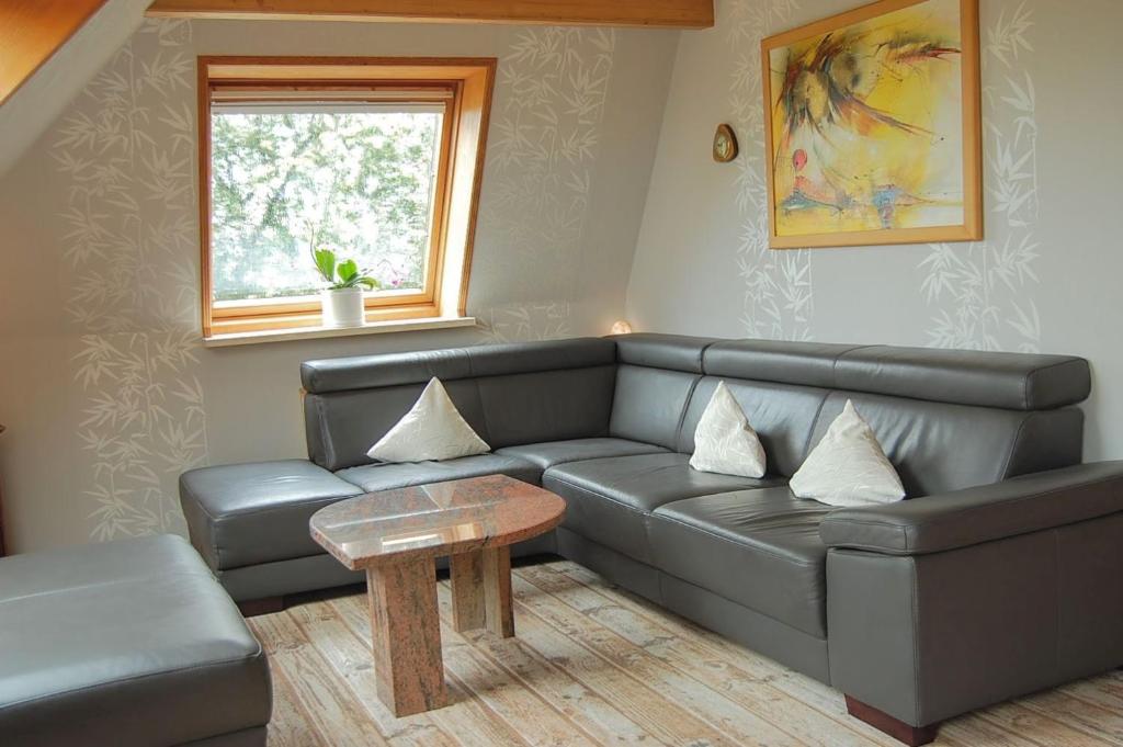 a living room with a leather couch and a table at Ferienwohnung Sonne & Sauna in Sönnebüll