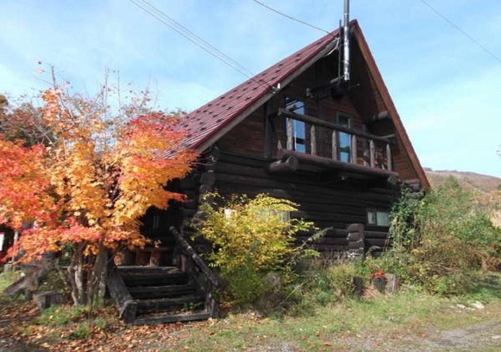 eine alte Blockhütte mit Fallfoliage davor in der Unterkunft Kameda-gun - Cottage / Vacation STAY 34923 in Nanae