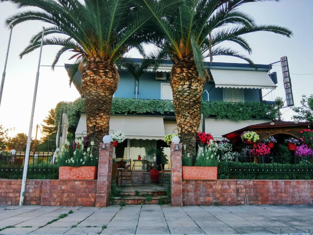 利瓦納泰的住宿－Hotel Akti，两棵棕榈树,在一座建筑前