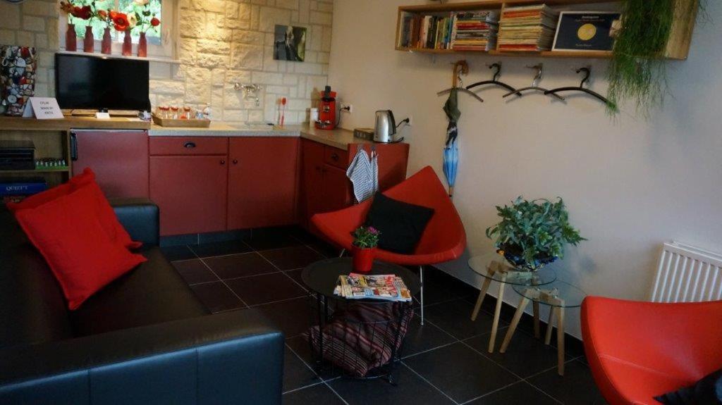 a living room with red chairs and a kitchen at Huize Mesch in Eijsden