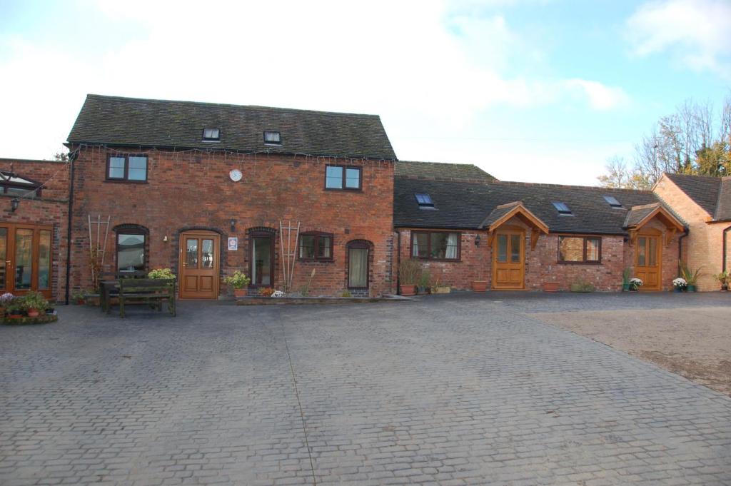 a large red brick building with a courtyard at Vale Farm in Higham on the Hill