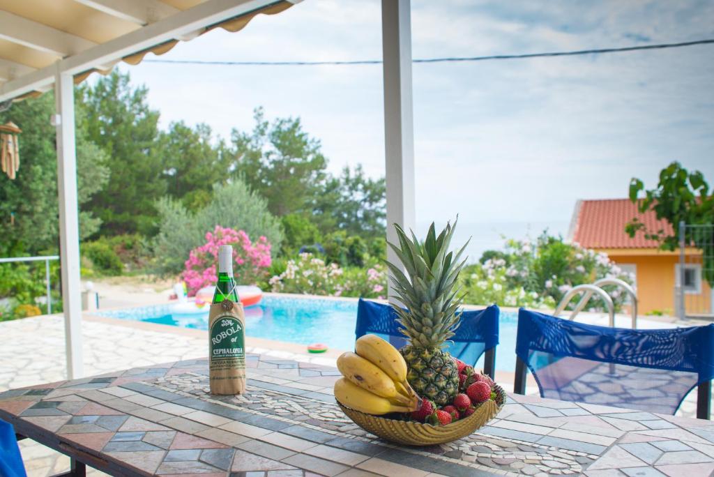 een tafel met een fruitschaal en een fles champagne bij Sarakiniko villa with private pool in Póros
