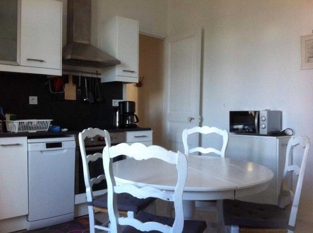 uma cozinha com uma mesa branca e 2 cadeiras brancas em Au coeur de bourg... em Saint-Lunaire