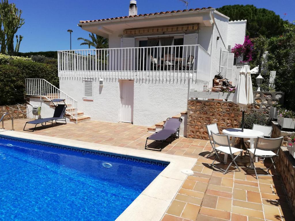 a villa with a swimming pool in front of a house at Xalet a primera linea de mar in Calafat