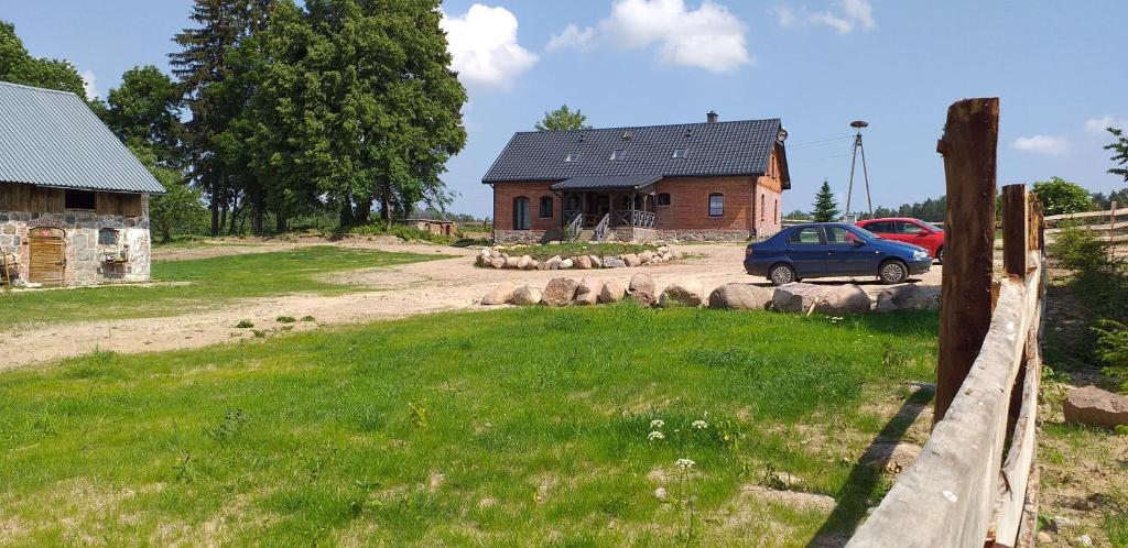 a house with a car parked in front of a yard at Zacisze przy lesie in Ryn