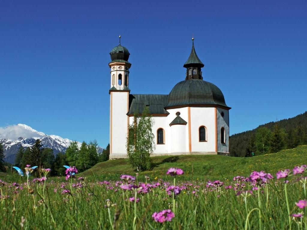 a church on a hill with a field of flowers at Appartmenthaus Birkenwald in Seefeld in Tirol