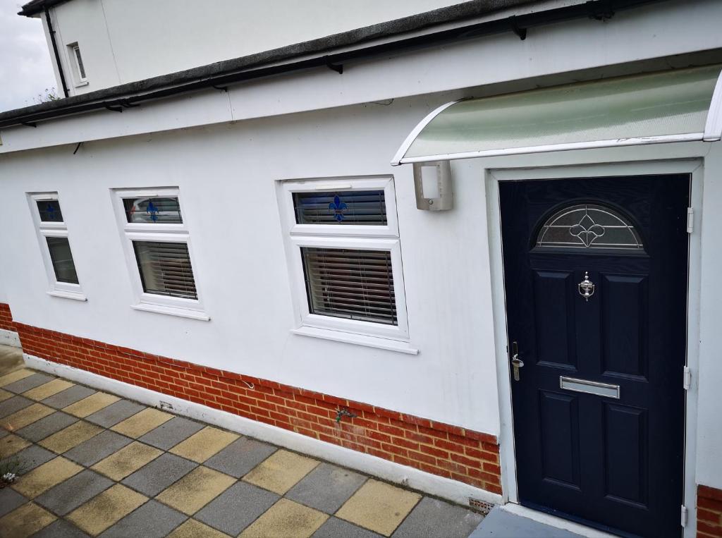 a white house with a blue door and windows at 2 ROOMS ANNEX (TV+WiFi) in Chigwell