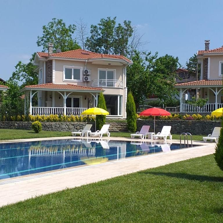a house with a swimming pool with chairs and umbrellas at PALACE KIRKPINAR in Sakarya
