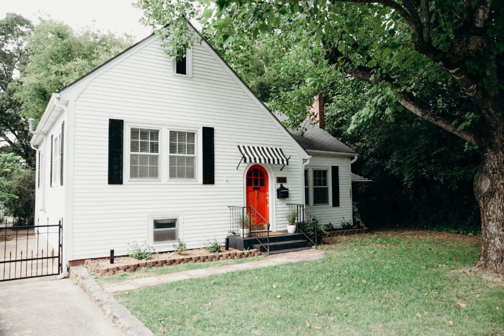 ein weißes Haus mit einer roten Tür und einem Baum in der Unterkunft The Paddock Luxury Vacation Home in Hot Springs