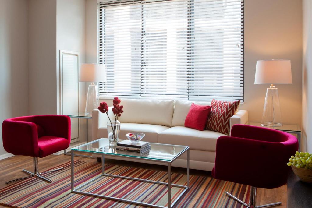 a living room with a white couch and two red chairs at Furnished Quarters at 15/25 Bank Street in White Plains