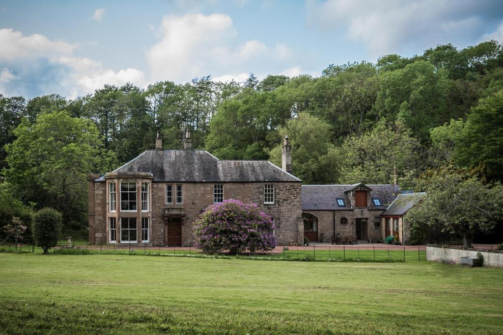 an old stone house with a grass yard at Glenarch House in Dalkeith