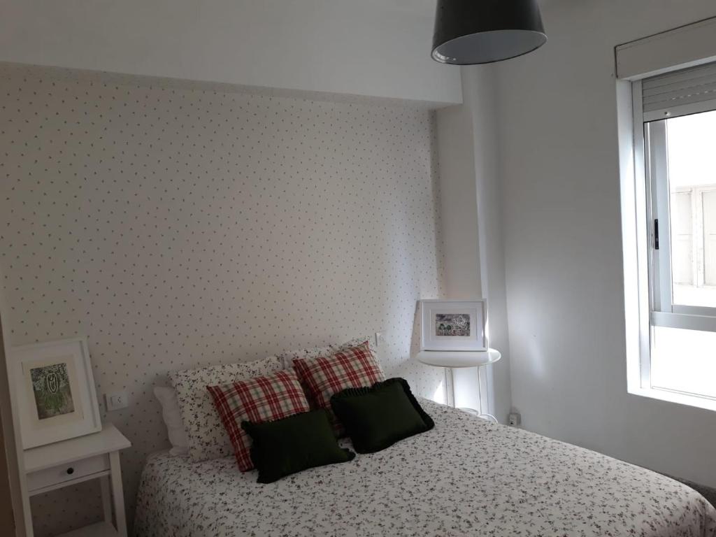 Un dormitorio con una cama con almohadas verdes y una ventana en Casa rosiña, en Sanxenxo