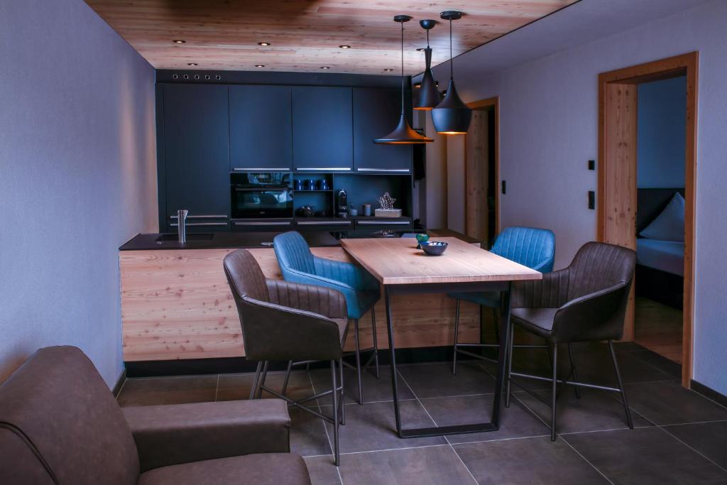 une cuisine avec une table en bois et des chaises bleues dans l'établissement Alpinlodge Ladis, à Ladis