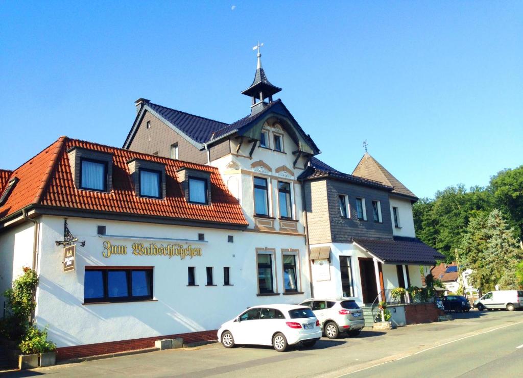 un grande edificio bianco con macchine parcheggiate di fronte di Hotel Waldschlösschen a Füchten