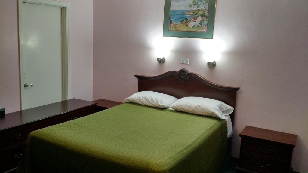 a bedroom with a green bed with two pillows at El Rancho Motel in Watsonville