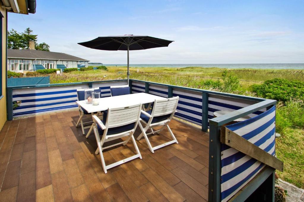 une terrasse avec une table, des chaises et un parasol dans l'établissement Skærven Beachfront Apartments and Cottage, à Nyborg