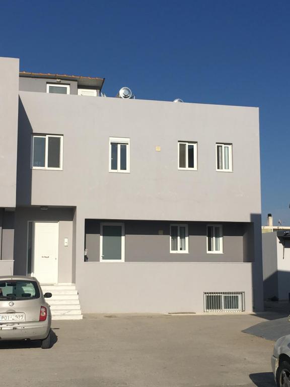 a white building with a car parked in a parking lot at Retas apartment up in Kremasti