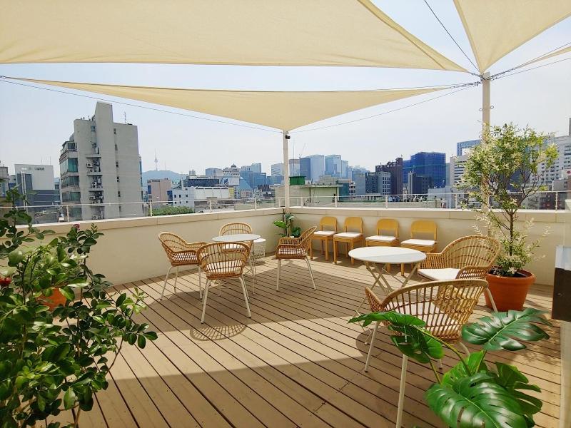 balcón con sillas, mesas y sombrilla en Tong Tong Petit Hotel en Seúl