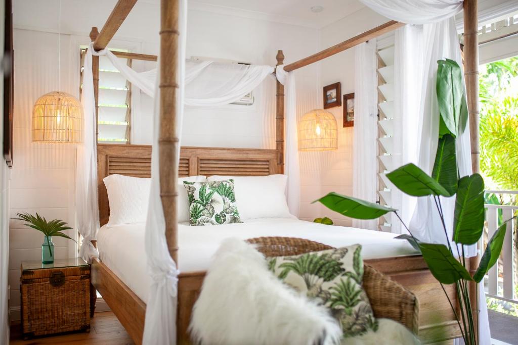 a bedroom with a canopy bed with white curtains at Pandanus Cottage in Port Douglas