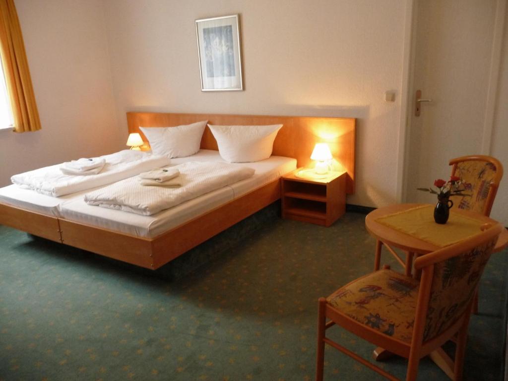 a bedroom with a bed and a table and a chair at Hotel Garni am Schlosspark in Wernigerode