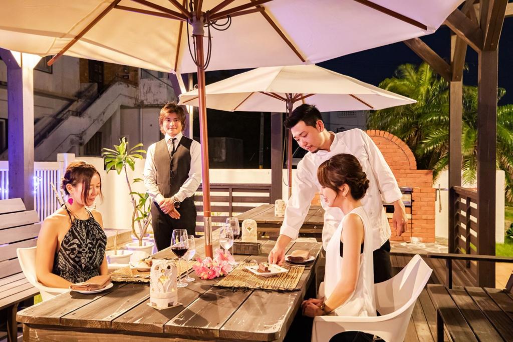a man and a woman sitting at a table with a table at Kerama Terrace in Tokashiki