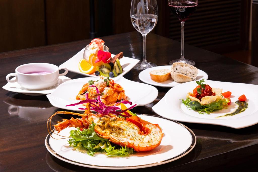 a table with plates of food and a glass of wine at Kerama Terrace in Tokashiki