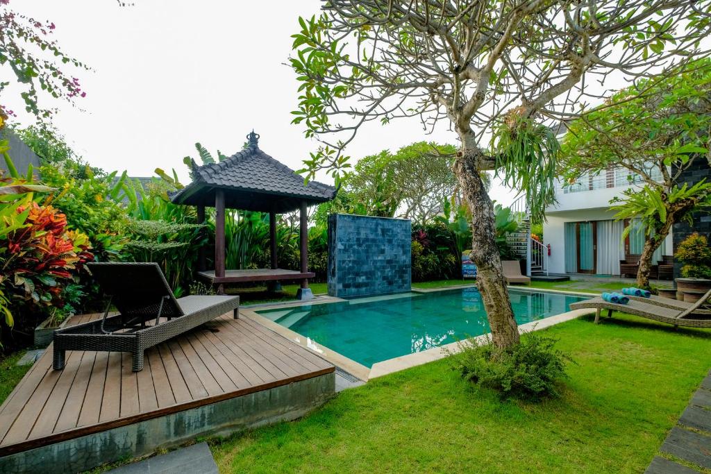 - une piscine avec une chaise et un parasol à côté d'un arbre dans l'établissement Papillon Echo Beach, à Canggu