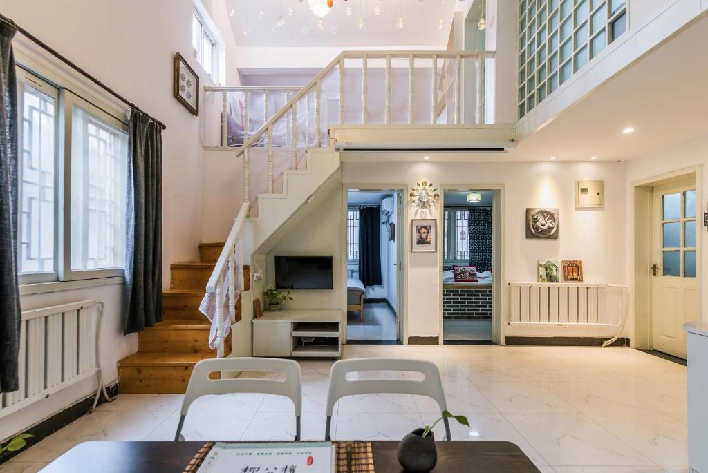 a living room with a staircase and white chairs at Ancient City Wall Home Apartment Xi'an in Xi'an