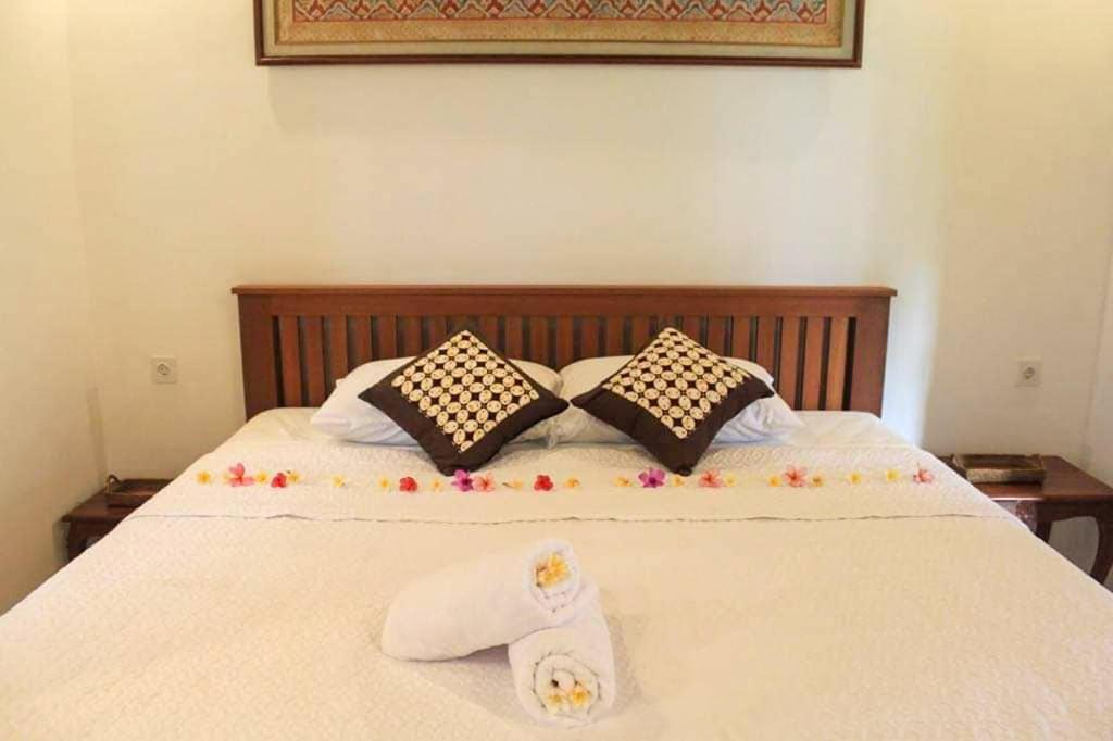 a bed with two pillows and two towels on it at Arsa Wayan Guest House in Klungkung