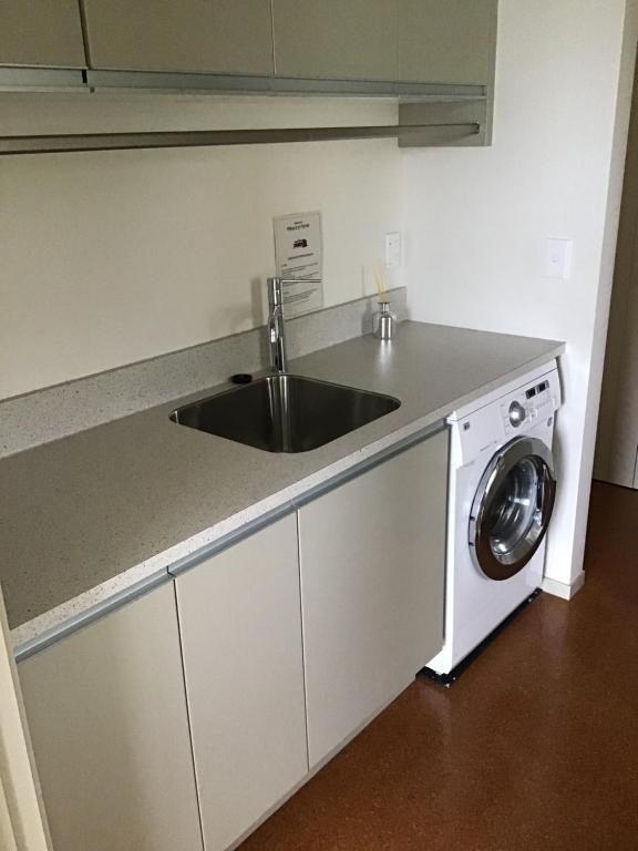 een keuken met een wastafel en een wasmachine bij Nikau’s on Palmer in Foxton Beach