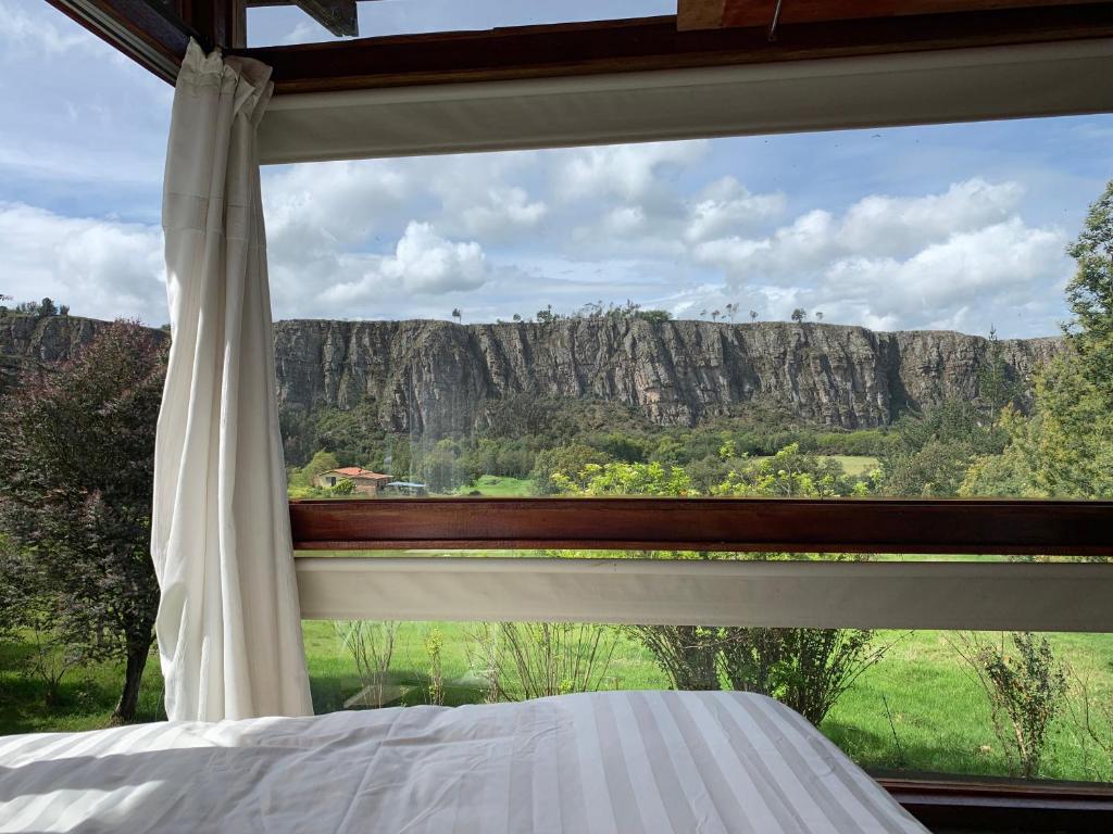ventana de un dormitorio con vistas a la montaña en Casa en el Árbol en Suesca
