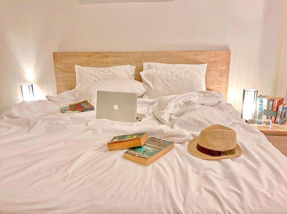 a bed with a hat and books and a laptop on it at Lemonade Phuket Hotel -SHA Plus in Chalong