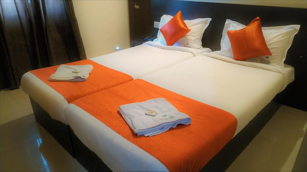 two beds in a hotel room with towels on them at Hotel Prathiba Heritage in Trivandrum