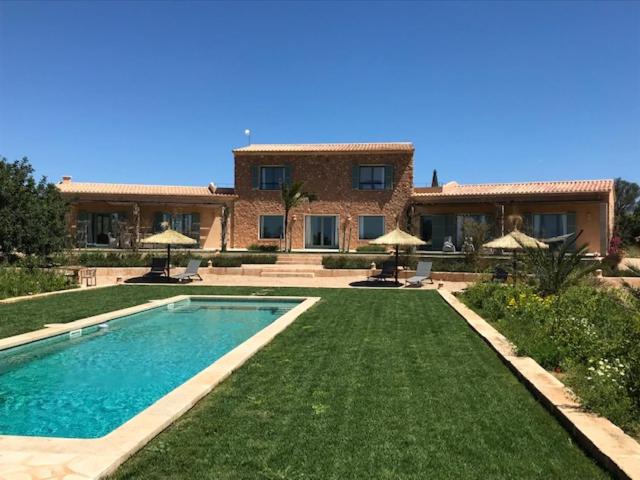 a house with a swimming pool in front of a yard at Finca El Idilio in Ses Salines