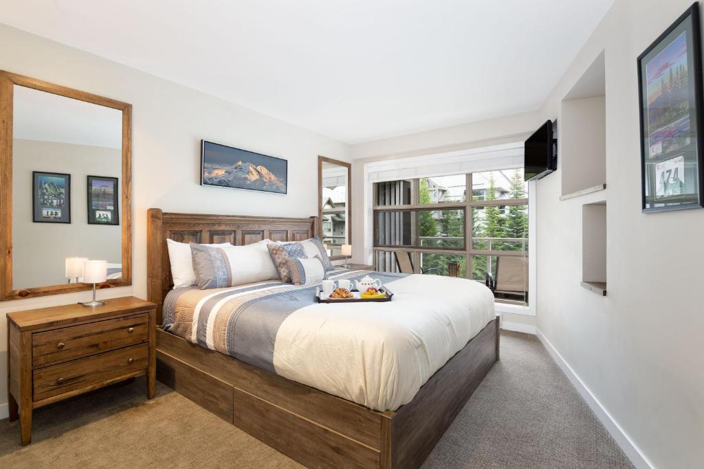 a bedroom with a large bed and a window at Aspens Mountain Side Resort in Whistler