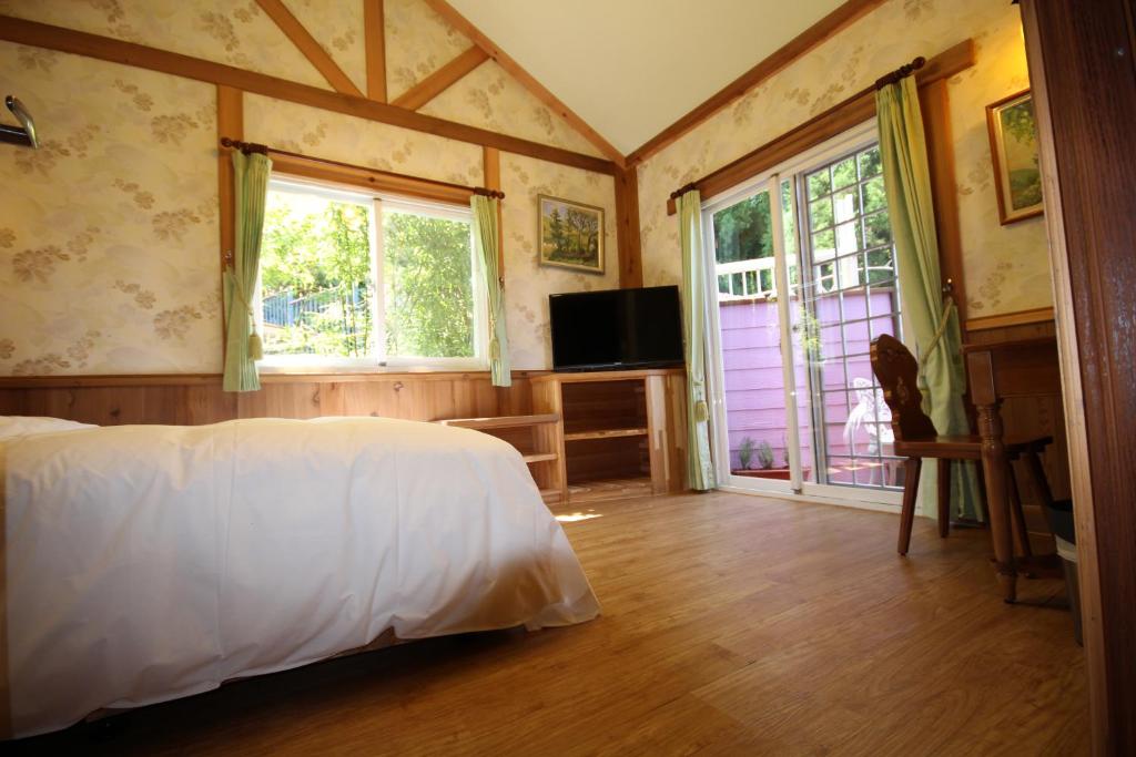 a bedroom with a bed and a tv and windows at Cingjing Vienna Pleasance Cottage in Ren&#39;ai