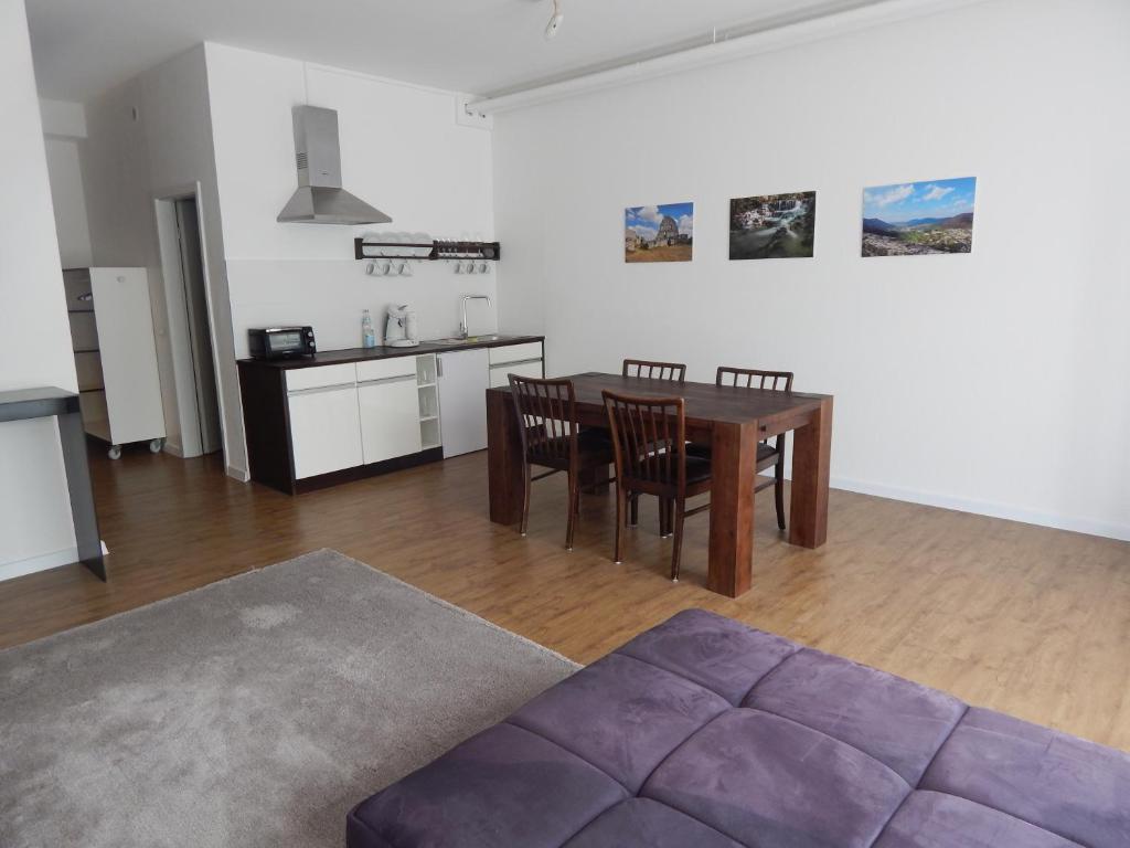 a living room with a table and chairs and a kitchen at FREE Apartment - Am Kurpark in Bad Urach