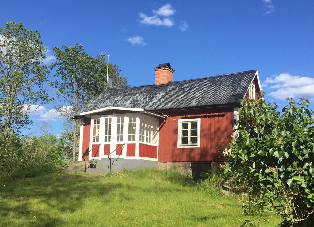 una casa roja con un techo negro en un campo en Malghults Gård en Kristdala