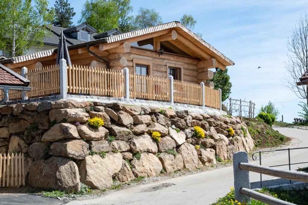 een blokhut met een stenen muur en een hek bij Chalet Ellerbeck in Langdorf