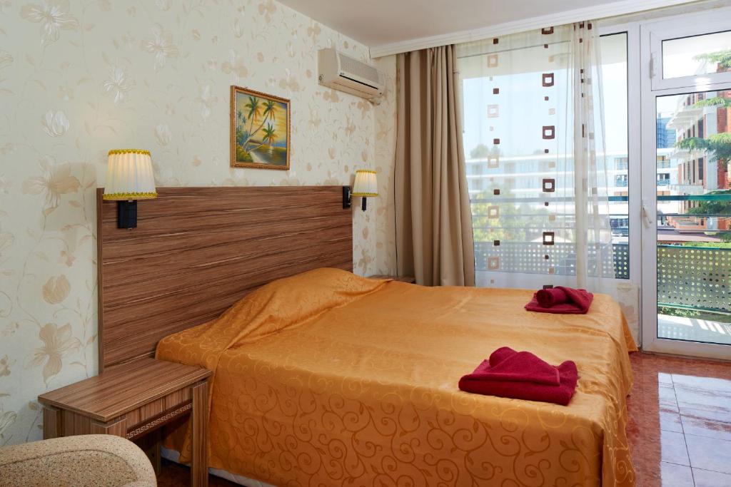 a bedroom with a bed and a large window at Hotel Yantra in Sunny Beach