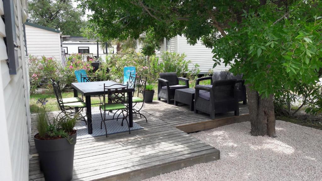 a wooden deck with a table and chairs and a tree at Mobil home récent clim 3ch Camping3* piscine in Argelès-sur-Mer