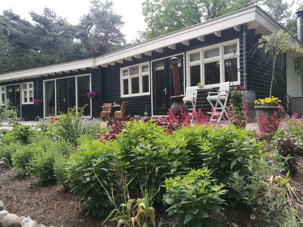 a black tiny house with flowers in the yard at Bosgeluk in Helmond