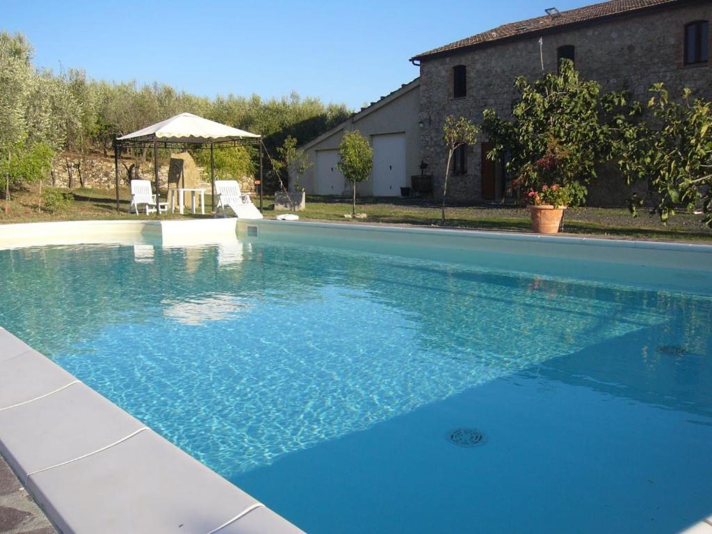 a large blue swimming pool in front of a house at Agriturismo Bio Le 4 Stagioni in Porrona