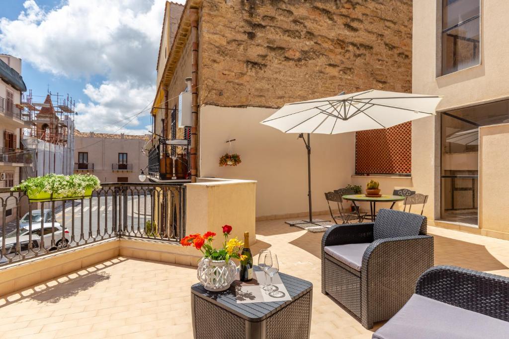 patio ze stołem, krzesłami i parasolem w obiekcie Residenza del Duca - Casteldaccia 2 camere w mieście Casteldaccia