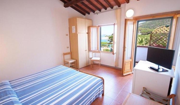 a bedroom with a bed and a desk with a television at La vela del veliero in SantʼAndrea